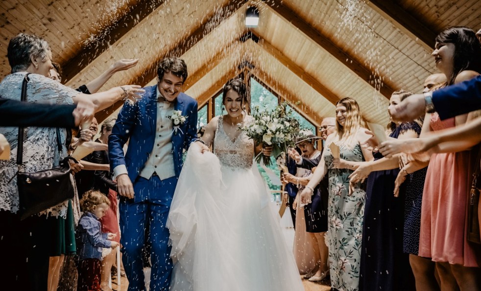 Couple have thrown rice on them after wedding ceremony in wooden building