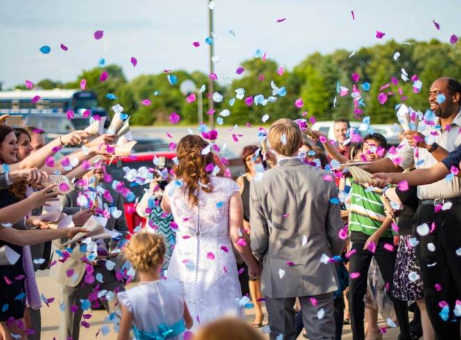 Bride and groom from behind walking through blue and pink petal confetti