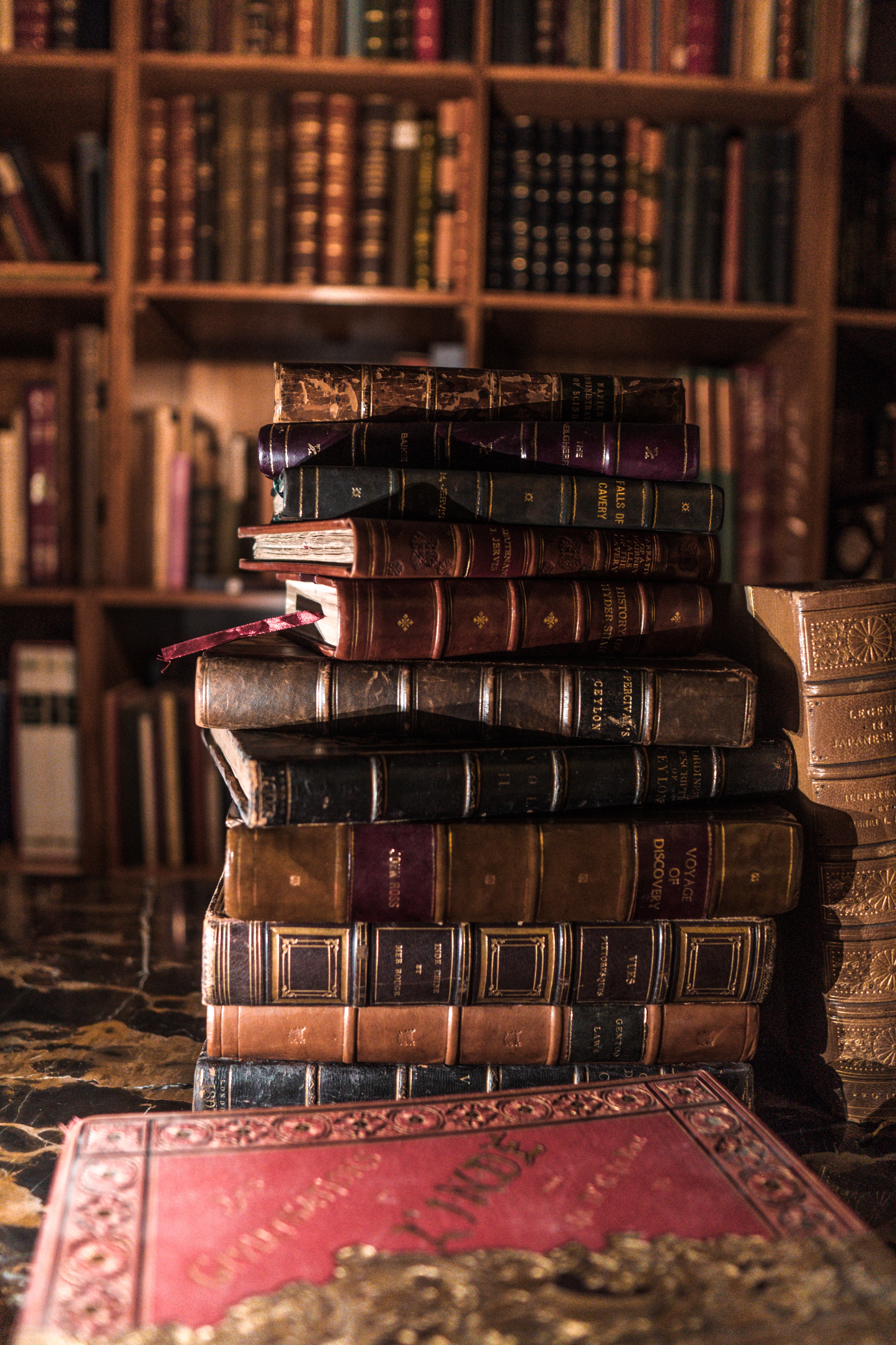 Vintage books stacked in front of shelves filled with vintage books