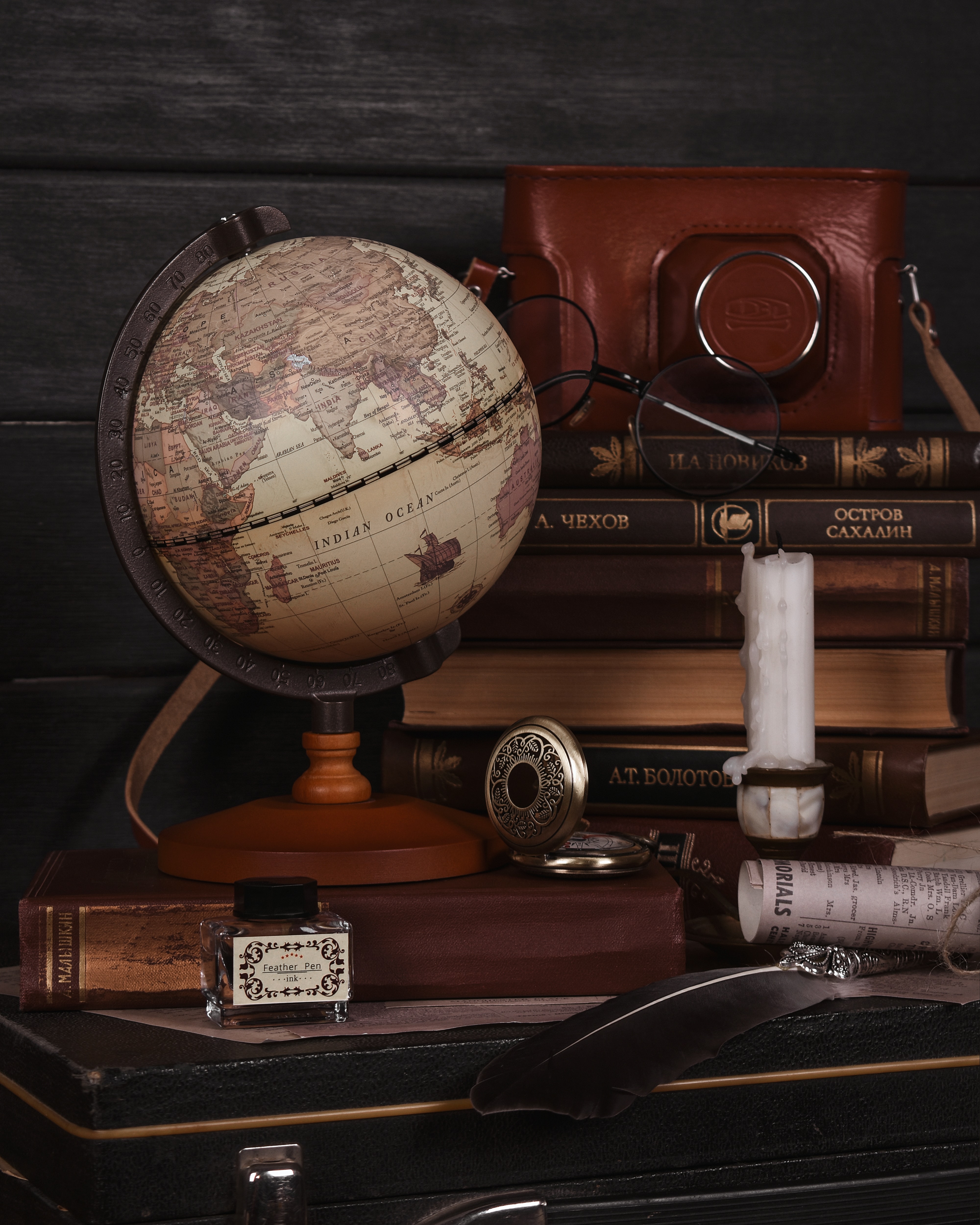 Display of vintage camera bag, books, globe, inkwell and pocket watch